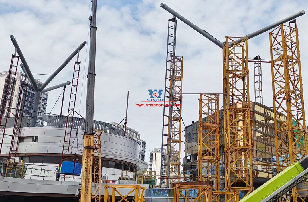 Recently, Shaoxing Huafa Financial Vitality City ETFE membrane structure commercial canopy ushered in new progress.  Shaoxing Huafa Financial Vitality City is located in Jinghu New District, Yuecheng District, Shaoxing City, 7.5km away from Shaoxing City Center, east to Xingzhong Road, west to Wenxian Road, south to Qunxian Road, north to Kwun Tong Road West. Huafa Financial Vitality City is the first commercial flagship brand of Guomai Huafa into Zhejiang, based on the history and future of Shaoxing, located in Jinghu high-end core, to create a construction surface of about 70,000 square meters of MALL BLOCK commercial street combination of urban creative consumption space. The vertical support system of the main steel structure of the canopy is a tree structure, the horizontal support system is a double-curved box lattice shell structure, and the steel columns and diagonal braces are all hoisted in a single hoisting mode. The roof lattice shell is assembled in blocks by automobile crane on the ground, and the crawler crane is hoisted in blocks. Finally, it is covered with ETFE film (soft glass). Make the whole commercial street more transparent and bright, dazzling.   The steel structure installation and splicing work is being carried out at the site. Due to the narrow space, the steel structure hoisting operation radius is large, and the on-site welding amount is large, and the recent attacks of high temperature and heavy rain have brought many tests to the project. According to the actual working conditions on the site, Marriott disassembled the steel structure hoisting section and calculated the hoisting equipment; And according to the actual situation of the project to organize relevant technical personnel to carry out targeted learning and understanding, multiple training. Establish BIM model to guide factory processing and on-site installation, adopt high-precision laser cutting, organize processing personnel and construction personnel to disclose information in special meetings, fully understand drawings and models, and provide a strong guarantee for project construction. Engineering quality is the control focus of each project, and this project is included in the company's key control projects. Throughout the construction process of the project, Marriott has always focused on this quality goal, increased human and material input, strengthened management, carried forward the company's key projects, and done a good job in the spirit of each project, implementing quality target management. In order to achieve the goal, Marriott has implemented the target value to each team according to the project, the responsibility to the person, and the site construction is meticulous. In order to ensure the smooth progress of the project, the construction staff of Marriott planned for the rainy day, inverted the schedule, thorough deployment, coordinated the allocation of resources from various parties, coordinated the allocation of personnel, materials and machines, communicated the operation technology and safety technology of the operation team in advance, and assembled, tested, accepted and obtained evidence of the steel structure mesh shell. During the construction process, in the face of hot and rainy summer weather, the engineering Department does a good job of heat prevention and flood control measures to ensure the safety of construction personnel, and fully promote the construction progress, all the construction personnel fight sunny days, grab rainy days, under the premise of ensuring safety and quality, and constantly promote the progress of steel structure assembly, creating conditions for the installation of membrane structure in the later period.   The smooth progress of the project laid a solid foundation for the completion of the 