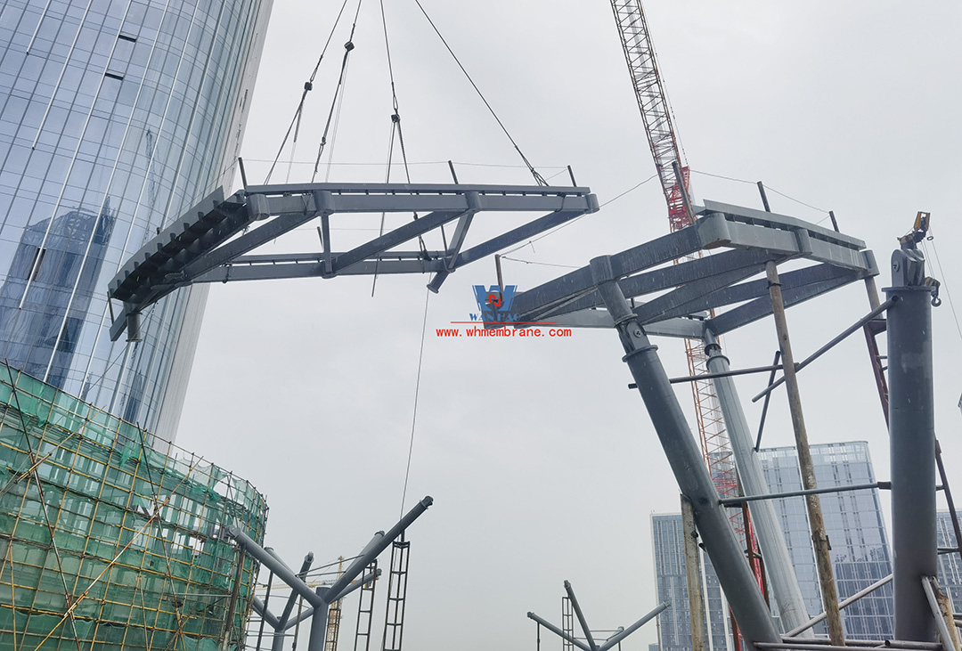 Recently, Shaoxing Huafa Financial Vitality City ETFE membrane structure commercial canopy ushered in new progress.  Shaoxing Huafa Financial Vitality City is located in Jinghu New District, Yuecheng District, Shaoxing City, 7.5km away from Shaoxing City Center, east to Xingzhong Road, west to Wenxian Road, south to Qunxian Road, north to Kwun Tong Road West. Huafa Financial Vitality City is the first commercial flagship brand of Guomai Huafa into Zhejiang, based on the history and future of Shaoxing, located in Jinghu high-end core, to create a construction surface of about 70,000 square meters of MALL BLOCK commercial street combination of urban creative consumption space. The vertical support system of the main steel structure of the canopy is a tree structure, the horizontal support system is a double-curved box lattice shell structure, and the steel columns and diagonal braces are all hoisted in a single hoisting mode. The roof lattice shell is assembled in blocks by automobile crane on the ground, and the crawler crane is hoisted in blocks. Finally, it is covered with ETFE film (soft glass). Make the whole commercial street more transparent and bright, dazzling.   The steel structure installation and splicing work is being carried out at the site. Due to the narrow space, the steel structure hoisting operation radius is large, and the on-site welding amount is large, and the recent attacks of high temperature and heavy rain have brought many tests to the project. According to the actual working conditions on the site, Marriott disassembled the steel structure hoisting section and calculated the hoisting equipment; And according to the actual situation of the project to organize relevant technical personnel to carry out targeted learning and understanding, multiple training. Establish BIM model to guide factory processing and on-site installation, adopt high-precision laser cutting, organize processing personnel and construction personnel to disclose information in special meetings, fully understand drawings and models, and provide a strong guarantee for project construction. Engineering quality is the control focus of each project, and this project is included in the company's key control projects. Throughout the construction process of the project, Marriott has always focused on this quality goal, increased human and material input, strengthened management, carried forward the company's key projects, and done a good job in the spirit of each project, implementing quality target management. In order to achieve the goal, Marriott has implemented the target value to each team according to the project, the responsibility to the person, and the site construction is meticulous. In order to ensure the smooth progress of the project, the construction staff of Marriott planned for the rainy day, inverted the schedule, thorough deployment, coordinated the allocation of resources from various parties, coordinated the allocation of personnel, materials and machines, communicated the operation technology and safety technology of the operation team in advance, and assembled, tested, accepted and obtained evidence of the steel structure mesh shell. During the construction process, in the face of hot and rainy summer weather, the engineering Department does a good job of heat prevention and flood control measures to ensure the safety of construction personnel, and fully promote the construction progress, all the construction personnel fight sunny days, grab rainy days, under the premise of ensuring safety and quality, and constantly promote the progress of steel structure assembly, creating conditions for the installation of membrane structure in the later period.   The smooth progress of the project laid a solid foundation for the completion of the 