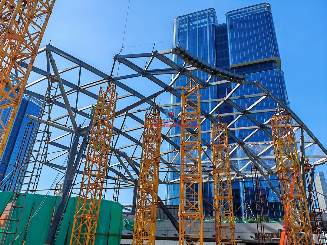 Recently, Shaoxing Huafa Financial Vitality City ETFE membrane structure commercial canopy ushered in new progress.  Shaoxing Huafa Financial Vitality City is located in Jinghu New District, Yuecheng District, Shaoxing City, 7.5km away from Shaoxing City Center, east to Xingzhong Road, west to Wenxian Road, south to Qunxian Road, north to Kwun Tong Road West. Huafa Financial Vitality City is the first commercial flagship brand of Guomai Huafa into Zhejiang, based on the history and future of Shaoxing, located in Jinghu high-end core, to create a construction surface of about 70,000 square meters of MALL BLOCK commercial street combination of urban creative consumption space. The vertical support system of the main steel structure of the canopy is a tree structure, the horizontal support system is a double-curved box lattice shell structure, and the steel columns and diagonal braces are all hoisted in a single hoisting mode. The roof lattice shell is assembled in blocks by automobile crane on the ground, and the crawler crane is hoisted in blocks. Finally, it is covered with ETFE film (soft glass). Make the whole commercial street more transparent and bright, dazzling.   The steel structure installation and splicing work is being carried out at the site. Due to the narrow space, the steel structure hoisting operation radius is large, and the on-site welding amount is large, and the recent attacks of high temperature and heavy rain have brought many tests to the project. According to the actual working conditions on the site, Marriott disassembled the steel structure hoisting section and calculated the hoisting equipment; And according to the actual situation of the project to organize relevant technical personnel to carry out targeted learning and understanding, multiple training. Establish BIM model to guide factory processing and on-site installation, adopt high-precision laser cutting, organize processing personnel and construction personnel to disclose information in special meetings, fully understand drawings and models, and provide a strong guarantee for project construction. Engineering quality is the control focus of each project, and this project is included in the company's key control projects. Throughout the construction process of the project, Marriott has always focused on this quality goal, increased human and material input, strengthened management, carried forward the company's key projects, and done a good job in the spirit of each project, implementing quality target management. In order to achieve the goal, Marriott has implemented the target value to each team according to the project, the responsibility to the person, and the site construction is meticulous. In order to ensure the smooth progress of the project, the construction staff of Marriott planned for the rainy day, inverted the schedule, thorough deployment, coordinated the allocation of resources from various parties, coordinated the allocation of personnel, materials and machines, communicated the operation technology and safety technology of the operation team in advance, and assembled, tested, accepted and obtained evidence of the steel structure mesh shell. During the construction process, in the face of hot and rainy summer weather, the engineering Department does a good job of heat prevention and flood control measures to ensure the safety of construction personnel, and fully promote the construction progress, all the construction personnel fight sunny days, grab rainy days, under the premise of ensuring safety and quality, and constantly promote the progress of steel structure assembly, creating conditions for the installation of membrane structure in the later period.   The smooth progress of the project laid a solid foundation for the completion of the 