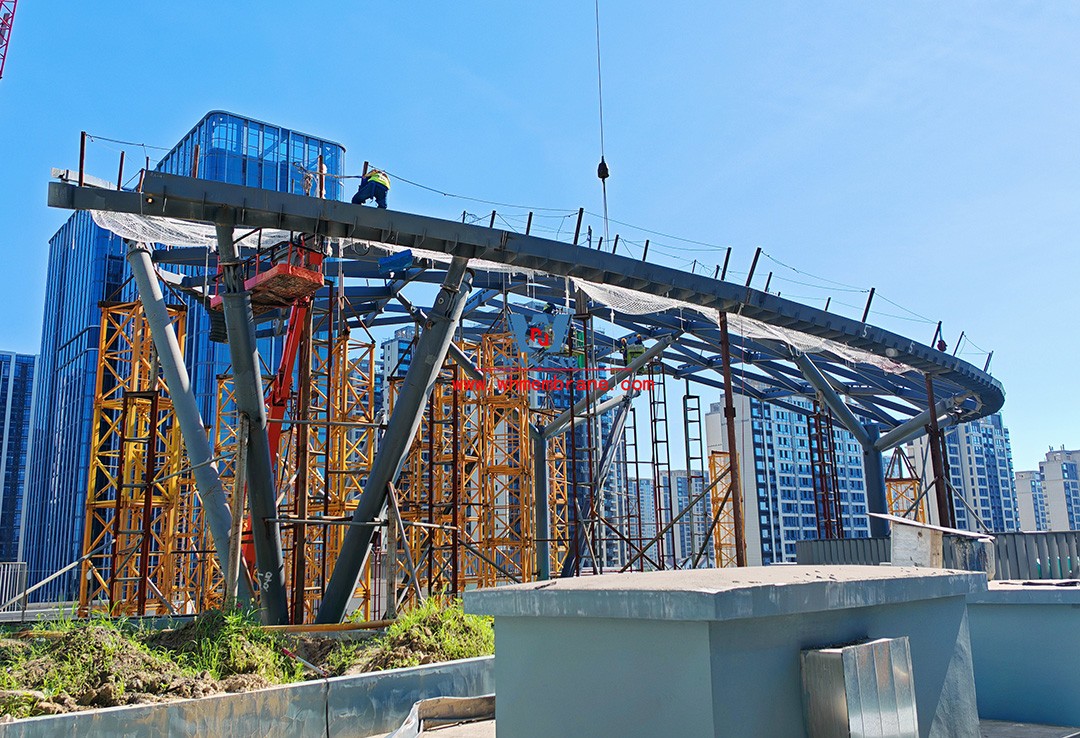Recently, Shaoxing Huafa Financial Vitality City ETFE membrane structure commercial canopy ushered in new progress.  Shaoxing Huafa Financial Vitality City is located in Jinghu New District, Yuecheng District, Shaoxing City, 7.5km away from Shaoxing City Center, east to Xingzhong Road, west to Wenxian Road, south to Qunxian Road, north to Kwun Tong Road West. Huafa Financial Vitality City is the first commercial flagship brand of Guomai Huafa into Zhejiang, based on the history and future of Shaoxing, located in Jinghu high-end core, to create a construction surface of about 70,000 square meters of MALL BLOCK commercial street combination of urban creative consumption space. The vertical support system of the main steel structure of the canopy is a tree structure, the horizontal support system is a double-curved box lattice shell structure, and the steel columns and diagonal braces are all hoisted in a single hoisting mode. The roof lattice shell is assembled in blocks by automobile crane on the ground, and the crawler crane is hoisted in blocks. Finally, it is covered with ETFE film (soft glass). Make the whole commercial street more transparent and bright, dazzling.   The steel structure installation and splicing work is being carried out at the site. Due to the narrow space, the steel structure hoisting operation radius is large, and the on-site welding amount is large, and the recent attacks of high temperature and heavy rain have brought many tests to the project. According to the actual working conditions on the site, Marriott disassembled the steel structure hoisting section and calculated the hoisting equipment; And according to the actual situation of the project to organize relevant technical personnel to carry out targeted learning and understanding, multiple training. Establish BIM model to guide factory processing and on-site installation, adopt high-precision laser cutting, organize processing personnel and construction personnel to disclose information in special meetings, fully understand drawings and models, and provide a strong guarantee for project construction. Engineering quality is the control focus of each project, and this project is included in the company's key control projects. Throughout the construction process of the project, Marriott has always focused on this quality goal, increased human and material input, strengthened management, carried forward the company's key projects, and done a good job in the spirit of each project, implementing quality target management. In order to achieve the goal, Marriott has implemented the target value to each team according to the project, the responsibility to the person, and the site construction is meticulous. In order to ensure the smooth progress of the project, the construction staff of Marriott planned for the rainy day, inverted the schedule, thorough deployment, coordinated the allocation of resources from various parties, coordinated the allocation of personnel, materials and machines, communicated the operation technology and safety technology of the operation team in advance, and assembled, tested, accepted and obtained evidence of the steel structure mesh shell. During the construction process, in the face of hot and rainy summer weather, the engineering Department does a good job of heat prevention and flood control measures to ensure the safety of construction personnel, and fully promote the construction progress, all the construction personnel fight sunny days, grab rainy days, under the premise of ensuring safety and quality, and constantly promote the progress of steel structure assembly, creating conditions for the installation of membrane structure in the later period.   The smooth progress of the project laid a solid foundation for the completion of the 